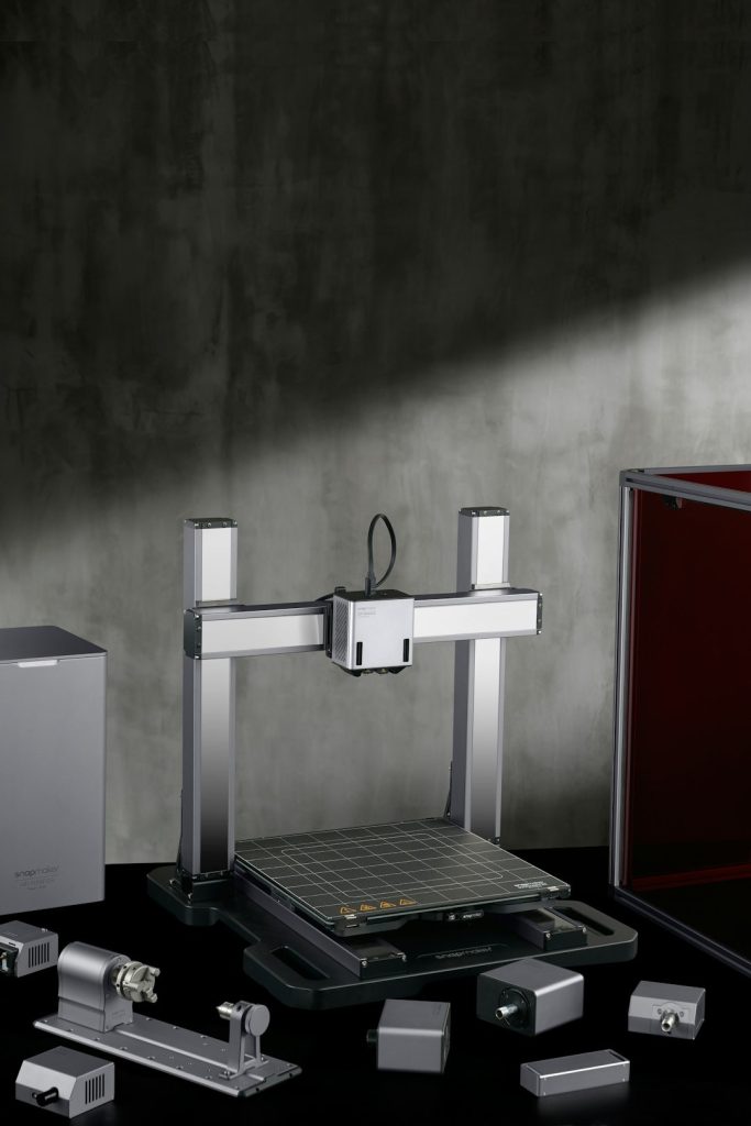 Modular 3D printer and CNC machine with tools on a reflective surface.
